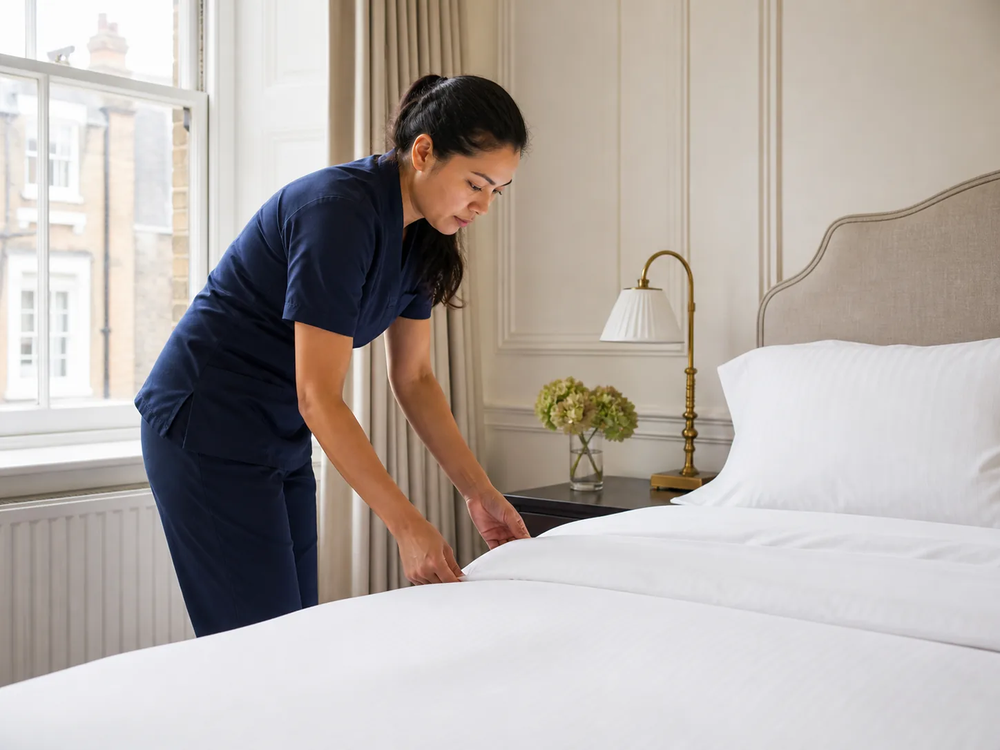 Professional cleaner making a guest bed in a Kensington apartment